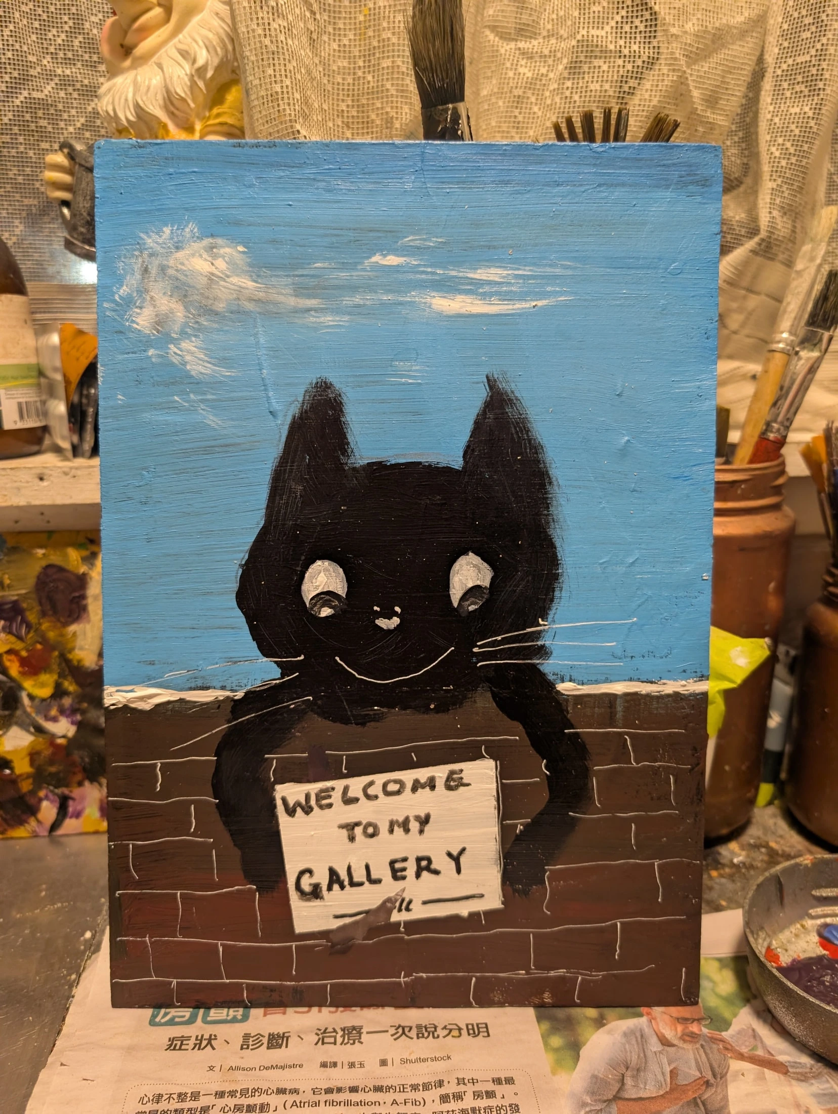 A black cat smiles over a brick wall, holding a sign painted WELCOME TO MY GALLERY beneath a blue sky.