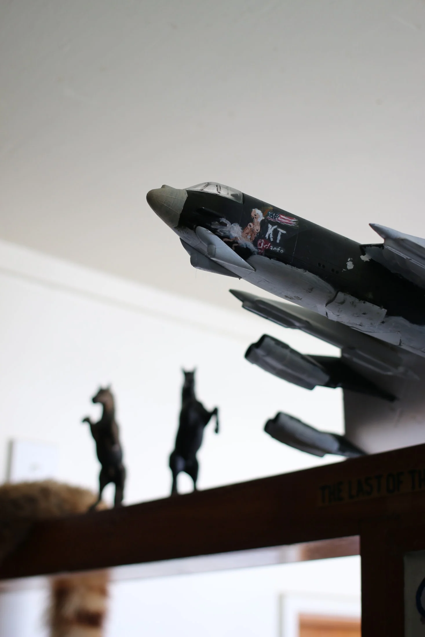 A model aircraft on a shelf above small horse figures.