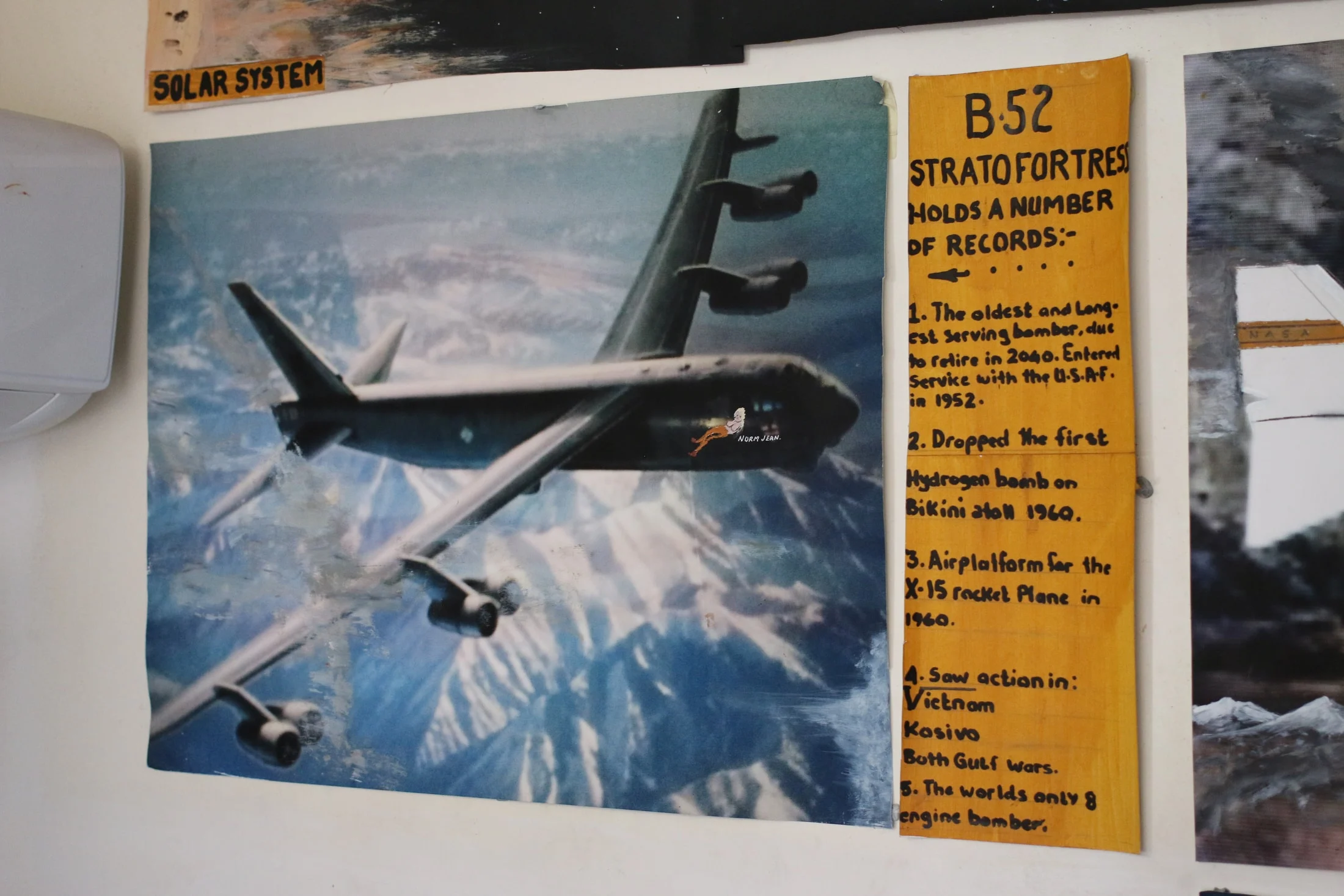 A B-52 aircraft picture and a handwritten information panel on the studio wall.
