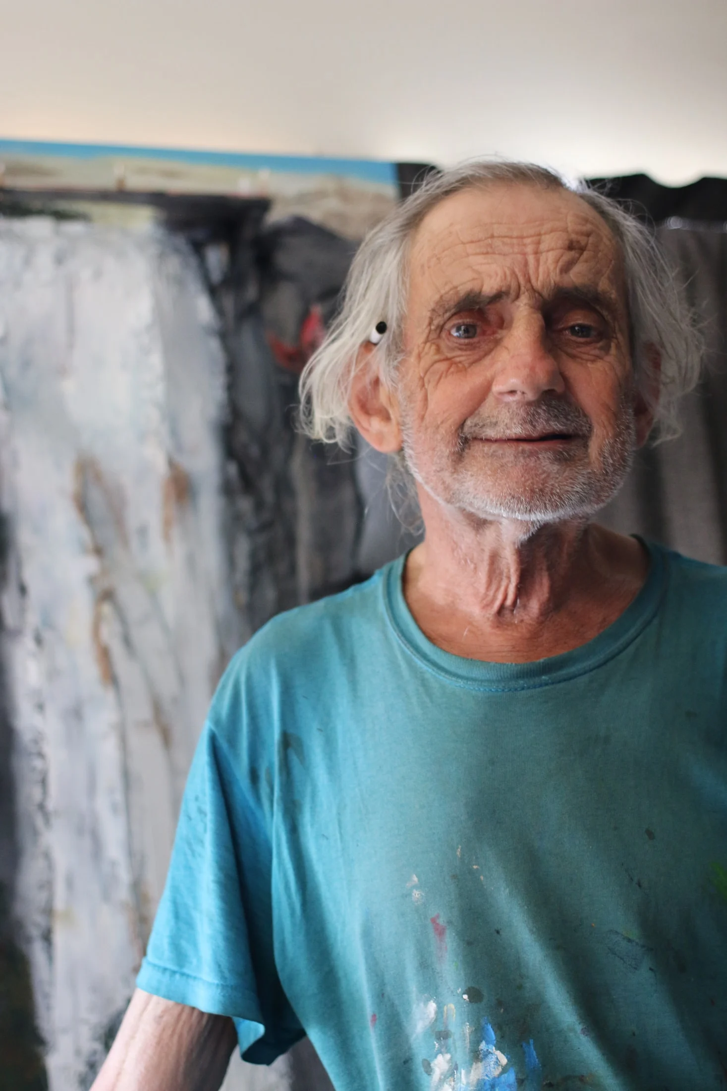 John wearing a turquoise, paint-marked shirt in his studio.