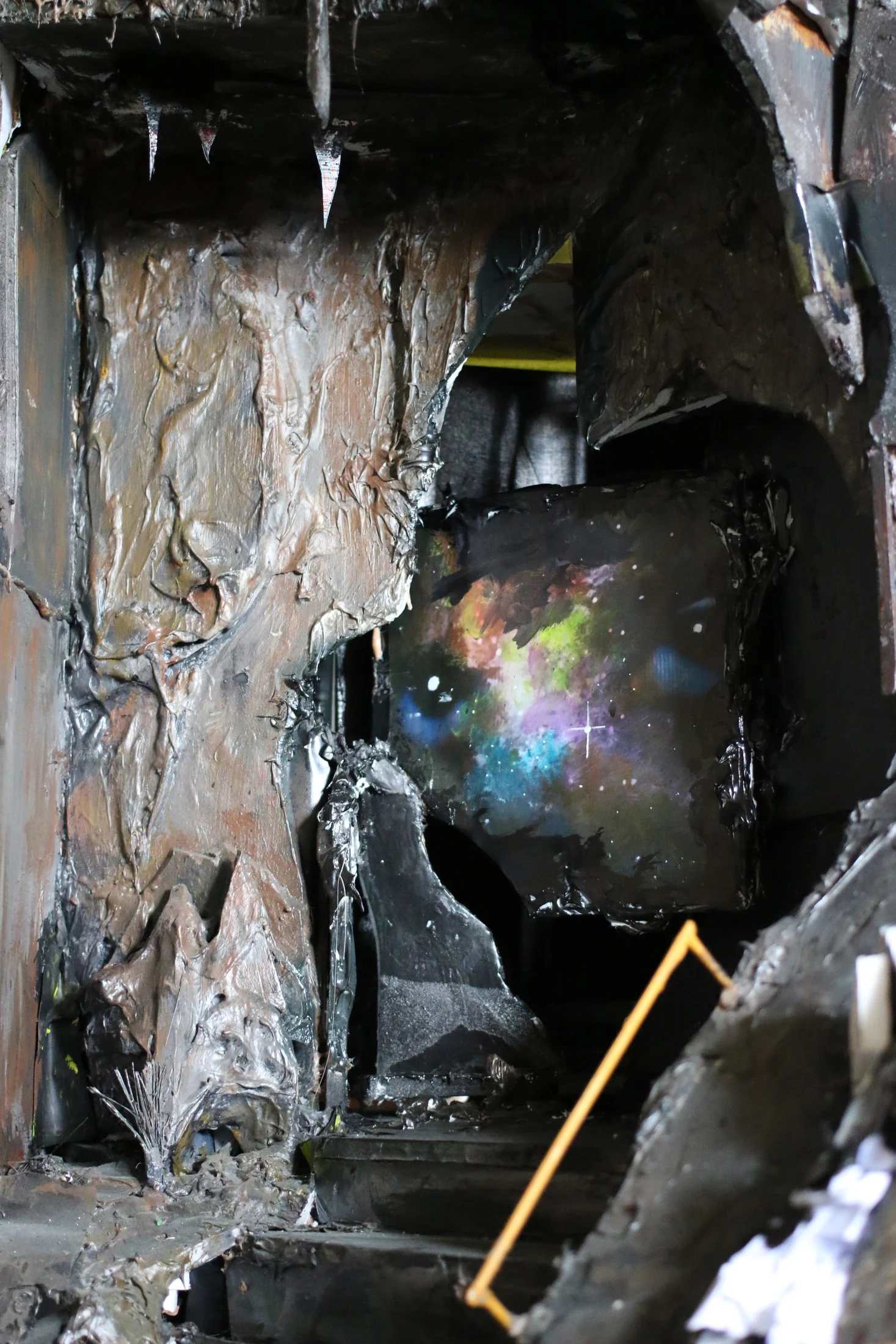 A wider view of a dark, textured studio piece with a colourful patch of stars inside.