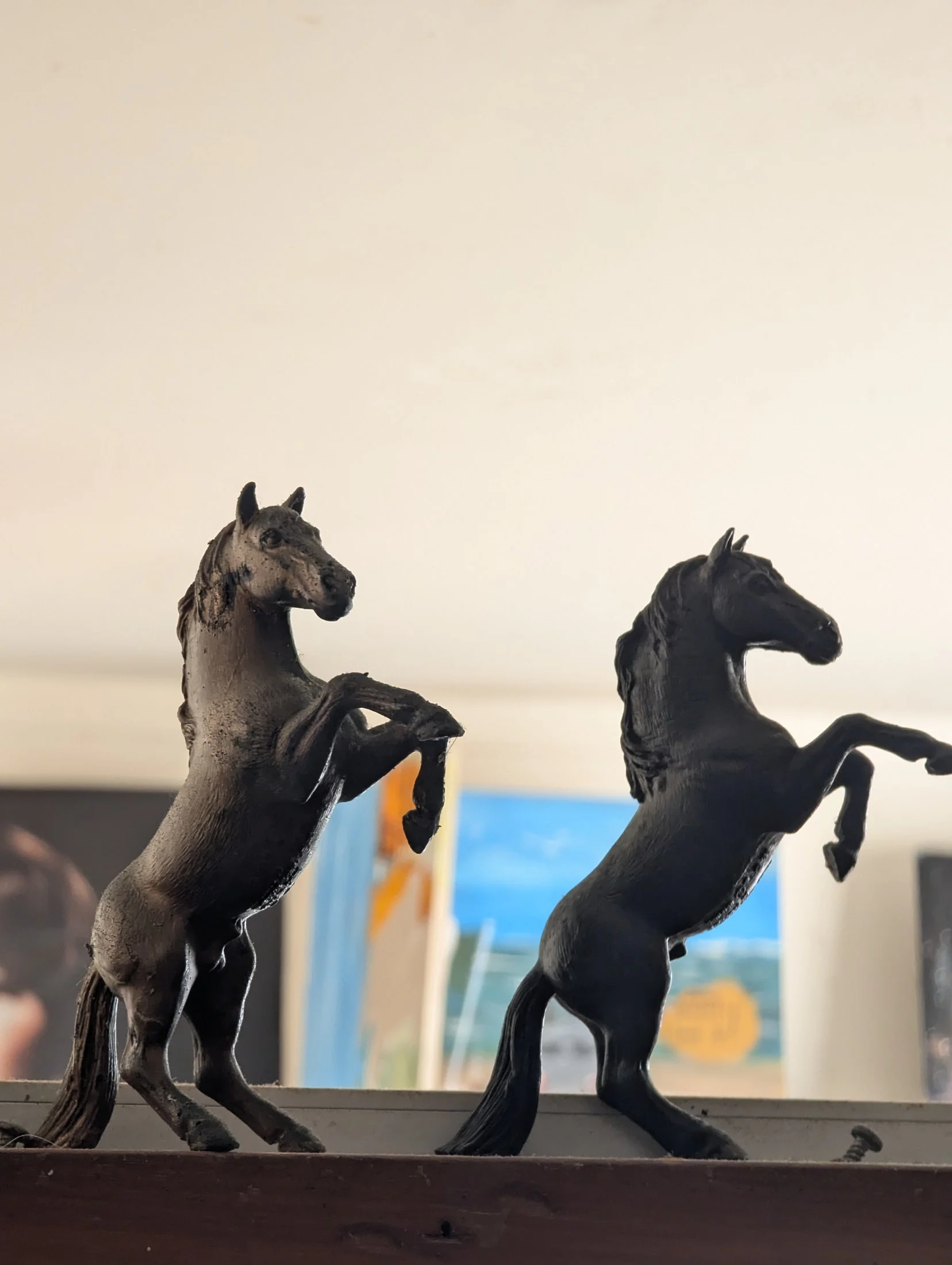 Two rearing horse figures on a wooden shelf.