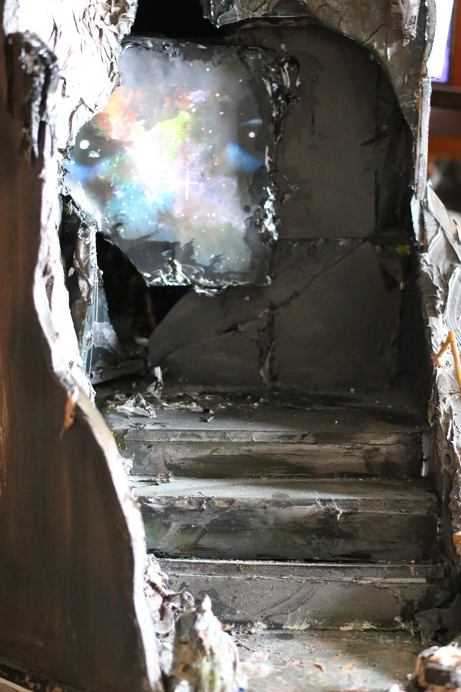 A view up the steps inside the sculpture towards a bright, multicoloured opening.